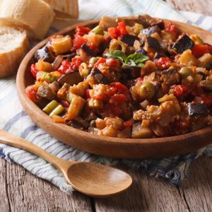 Ready to eat caponata on a wooden plate with spoon | AnnaMaria's