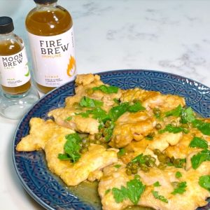 Chicken piccata with fire brew tonic vinegar on a blue plate - Chicken Brewata | AnnaMaria's